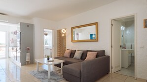 A modern living room with a grey sofa, a white coffee table, and a large mirror on the wall. - Apartment Tropicos (Carvoeiro)