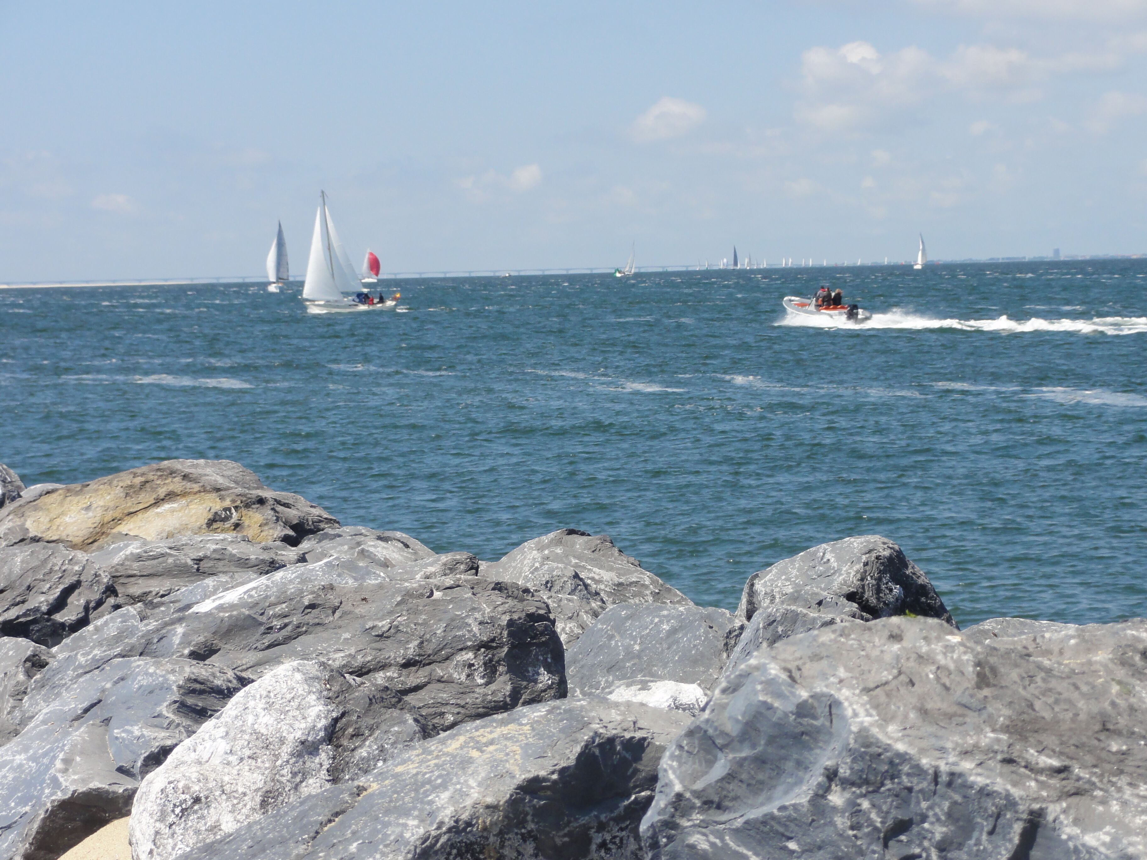 A rocky shoreline with boats on the water.