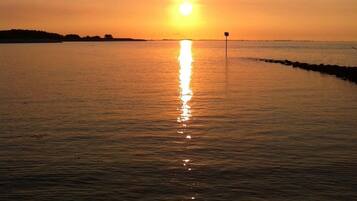 A sunset over a calm body of water with a distant shoreline.