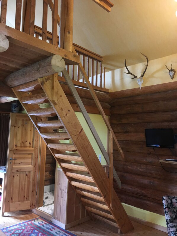 A wooden staircase with a handrail, a mounted television, and antler decorations on the wall.