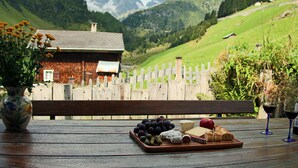 A wooden table with a cheese board, grapes, and wine glasses. - House in the middle of the Swiss Alps (Wassen)
