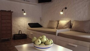 A compact living space with a sofa, a small table with a bowl of apples, and a wooden dresser. - House in the middle of the Swiss Alps (Wassen)