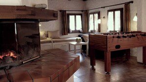 A cozy room with a fireplace, a foosball table, and a sofa. - House in the middle of the Swiss Alps (Wassen)