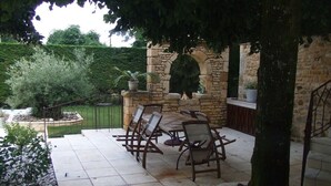 An outdoor patio with stone flooring, a stone fireplace, and a dining area with chairs and tables. - Independent house with heated pool (Perigord Noir hamlet) (CARLUX)