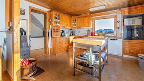 A spacious kitchen with wooden cabinets, a central island, a stove, and a view of mountains through the window.