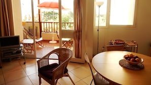 Ein Zimmer mit Esstisch, Stühlen, Fernseher und einem Balkon mit Aussicht.