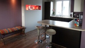 A modern kitchen with a bar area, a bench, and a window with natural light. - Bright tastefully decorated house 300 meters from the Sables Blancs beach. (Concarneau)