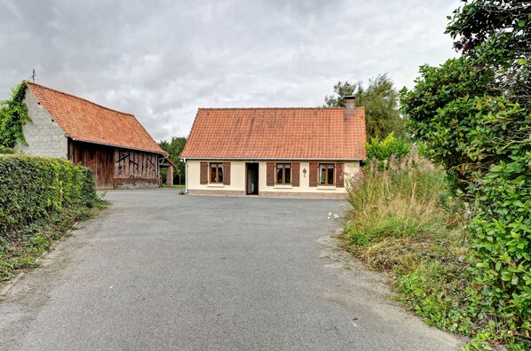 A rural property with two buildings, one with a sloped roof and another with a flat roof, surrounded by greenery.
