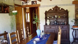 Una mesa de madera con sillas, un florero con plantas verdes y un mantel individual azul.