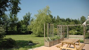 Una pérgola de madera con una mesa y bancos en un jardín.