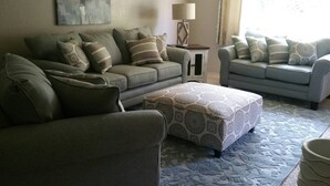 A living room with two sofas, a patterned ottoman, a lamp, and a painting on the wall. - Golf - Winery - Hike - Bike (Grand Junction)