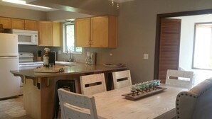 A kitchen with wooden cabinets, a microwave, a stove, and a dining area with a table and chairs. - Golf - Winery - Hike - Bike (Grand Junction)
