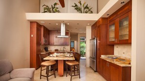 Une cuisine moderne avec des meubles en bois, un îlot central doté de tabourets et un réfrigérateur en acier inoxydable.