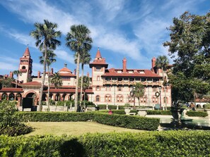 Un grand bâtiment historique doté de nombreuses tours et d’arcades, entouré de jardins bien entretenus et de palmiers.