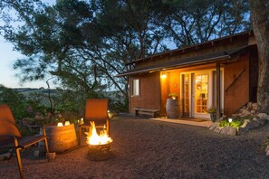 Un chalet rustique doté d’un foyer extérieur, de sièges pour se détendre en plein air et offrant une vue sur le paysage environnant.