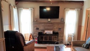 Un salon doté d’une cheminée, d’un ventilateur de plafond et d’un téléviseur à écran plat fixé au-dessus de la cheminée.
