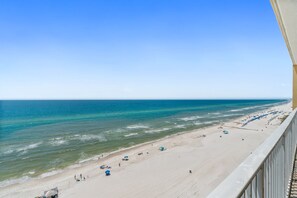 Uma praia com vista clara para o oceano, faixa de areia e alguns guarda-sóis.
