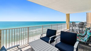 Ein Balkon mit Blick auf Strand und Meer. Zwei Stühle und ein Tisch befinden sich auf dem Balkon.