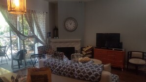 Ein Wohnzimmer mit einer Couch, einem Fernseher, einem Kamin und einem Essbereich mit Stühlen und einem Tisch.