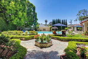 A pool area with a tiled patio, surrounded by well-maintained hedges and flowering plants. - Romantic Spanish Home, Private Pool, Walk to Beach (La Jolla)