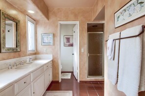 Un baño con lavamanos doble, ducha y toallero.