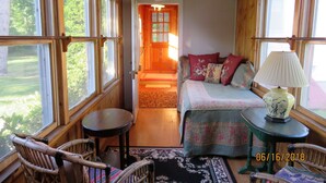 Une pièce confortable avec un lit, une table et une chaise, de grandes fenêtres et une porte en bois.