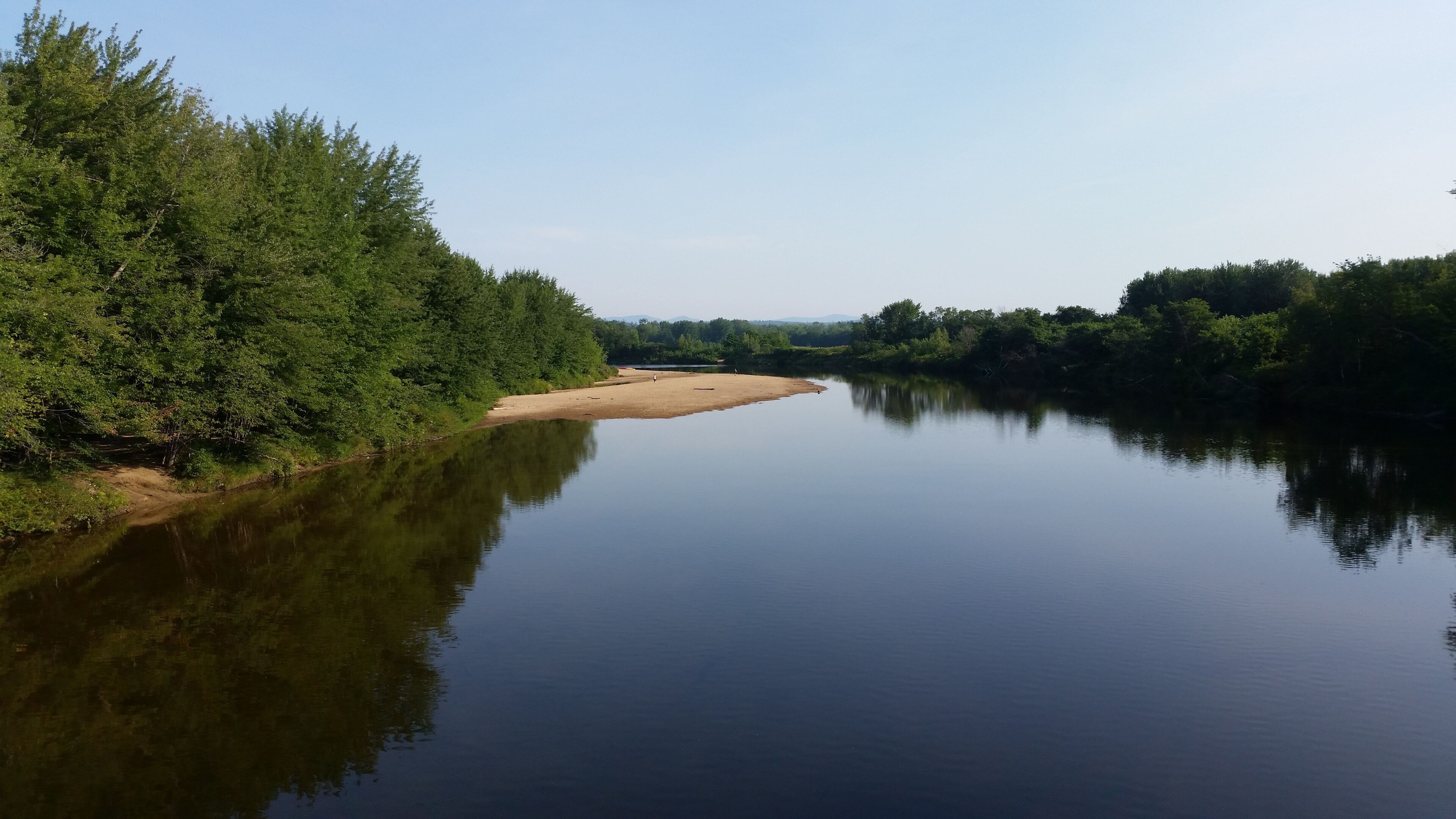A calm river with dense greenery on both sides.