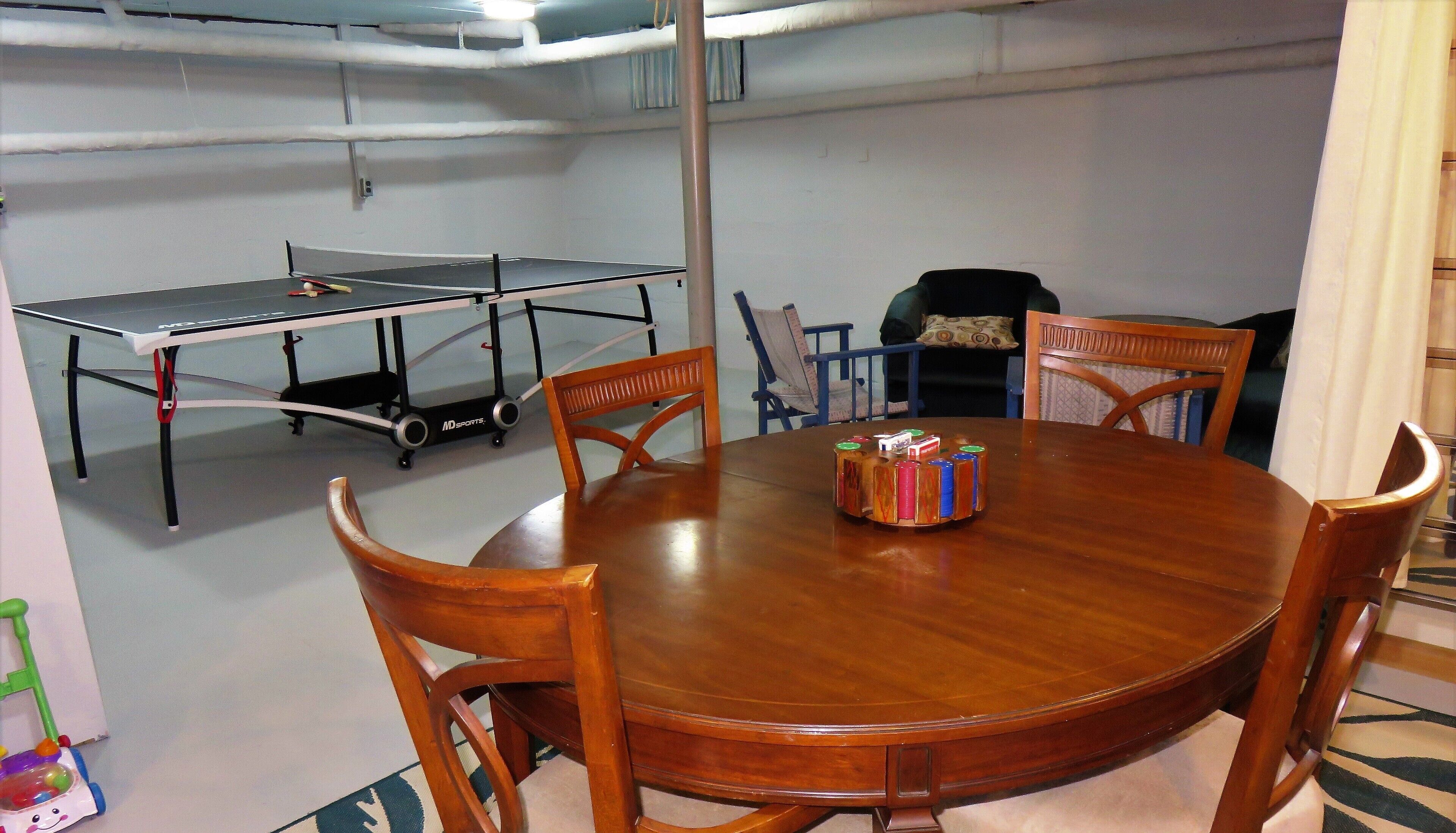 A room with a ping pong table, a wooden dining table with chairs, and a small toy car.