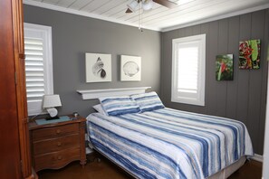 Une chambre à coucher avec un lit, une commode et des œuvres d’art accrochées au mur.