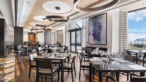 A modern restaurant with high ceilings, circular light fixtures, and large windows offering a view of the cityscape. - 4,000+ sq ft beachfront residence + PRIVATE BEACH Resort & Spa by Marriott (Fort Lauderdale)