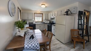 A compact kitchen with white cabinets, a refrigerator, and a dining area with a table and chairs. - Historic Building, Quiet Location in Beautiful Lancaster County, Stella Side (Terre HIll)