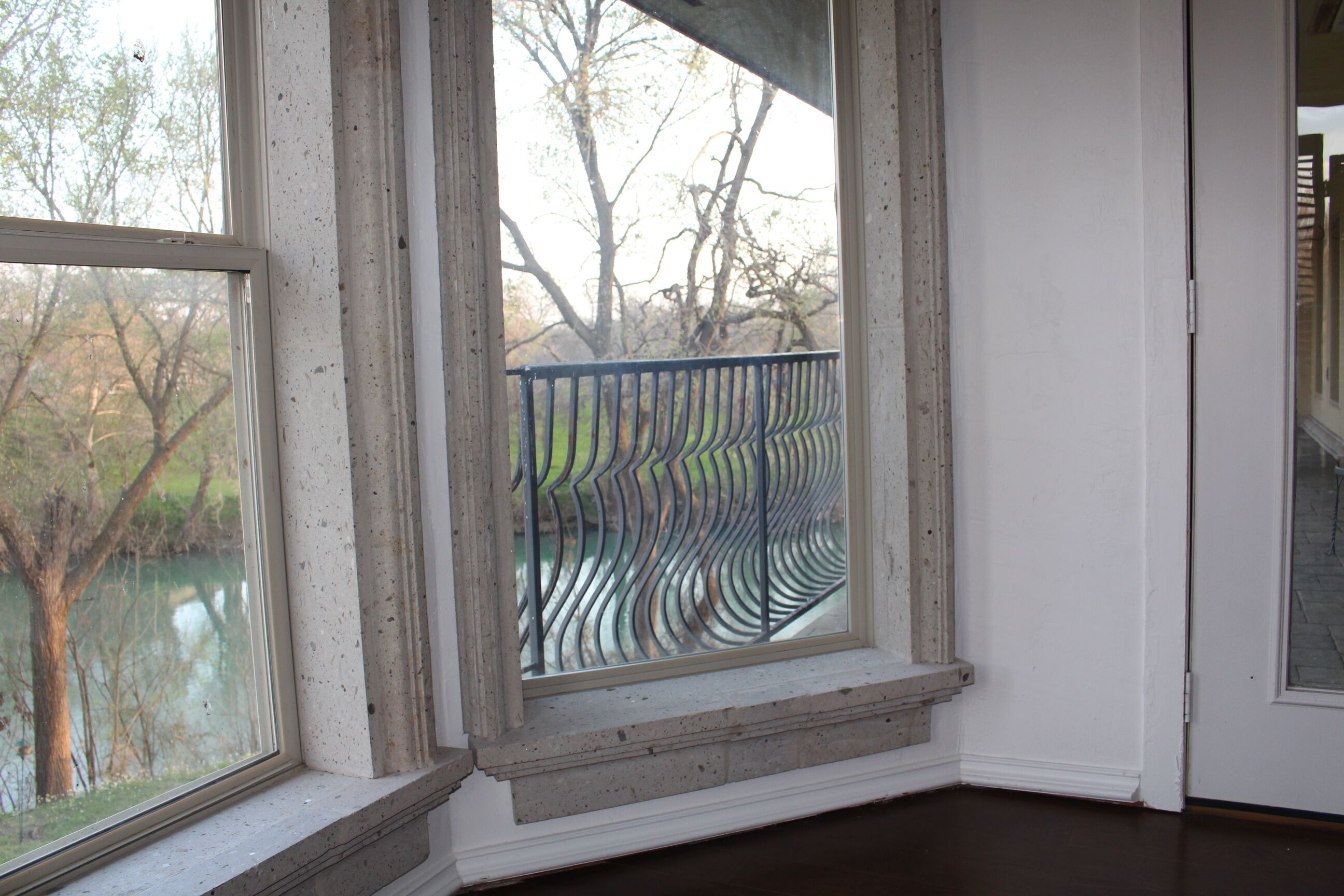 A room with a large window overlooking a body of water and trees.