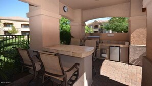 An outdoor patio area with a bar, seating, and a refrigerator.