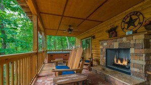 A covered porch with a stone fireplace, wooden furniture, and a star welcome sign.