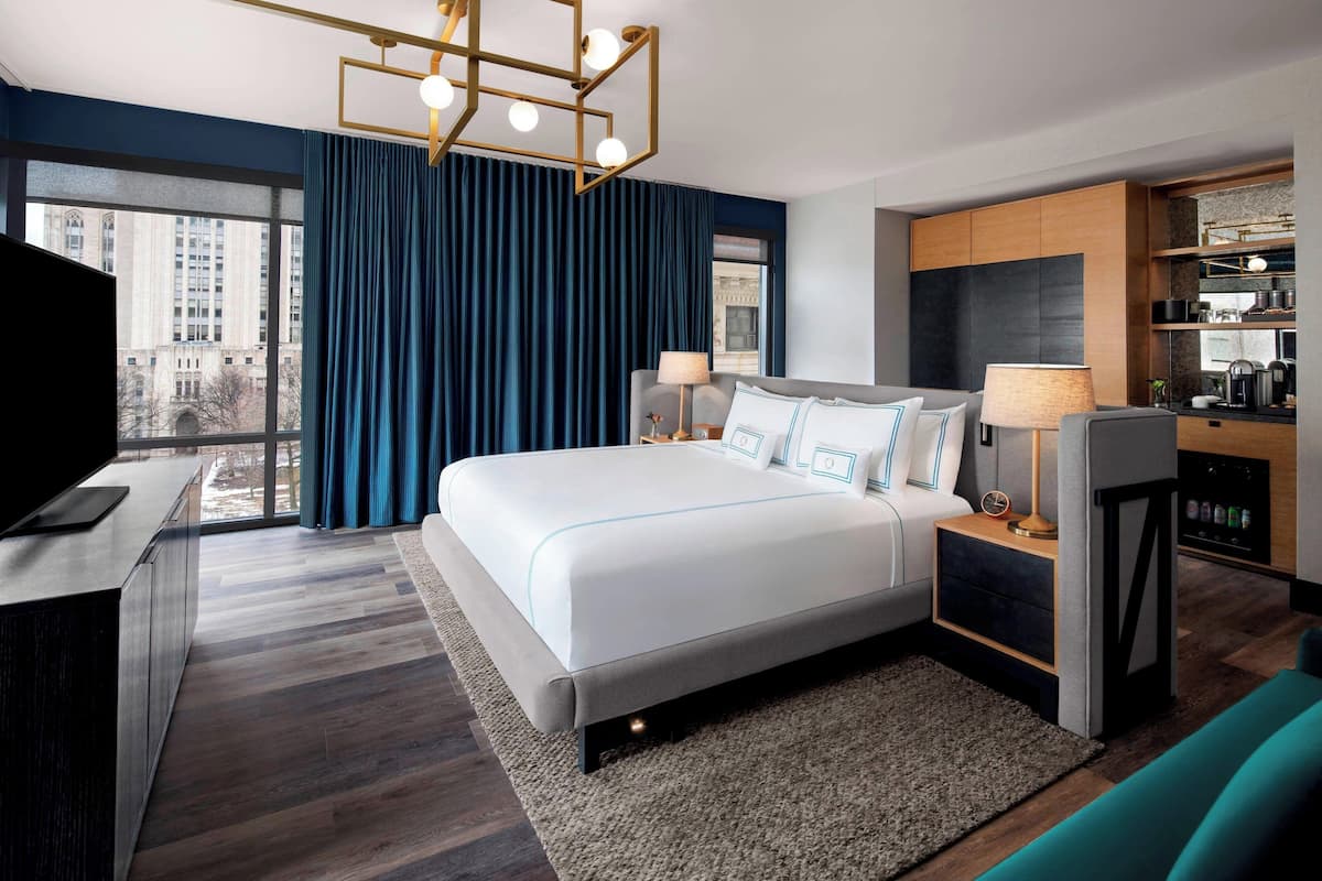 Une chambre d’hôtel moderne dotée d’un grand lit, d’une télévision, d’un bureau et offrant une vue sur la ville.