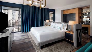 A modern hotel room with a large bed, a TV, a desk, and a view of the city.