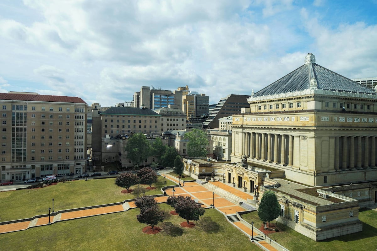 Un grand bâtiment doté d’un dôme imposant et de colonnes, entouré d’une pelouse bien entretenue et de sentiers.