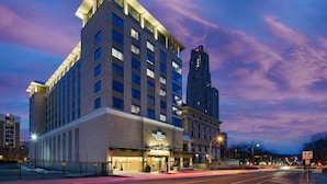 A modern hotel with a prominent entrance, multiple floors, and a tall adjacent building.