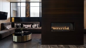 A modern living room with a dark wood floor, a sectional sofa with decorative pillows, a round coffee table, and a fireplace.