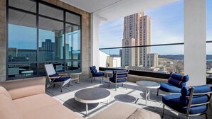 A modern rooftop lounge with large windows, blue seating, and a city view.