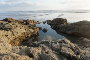 Una costa rocosa con aguas tranquilas que reflejan el cielo.