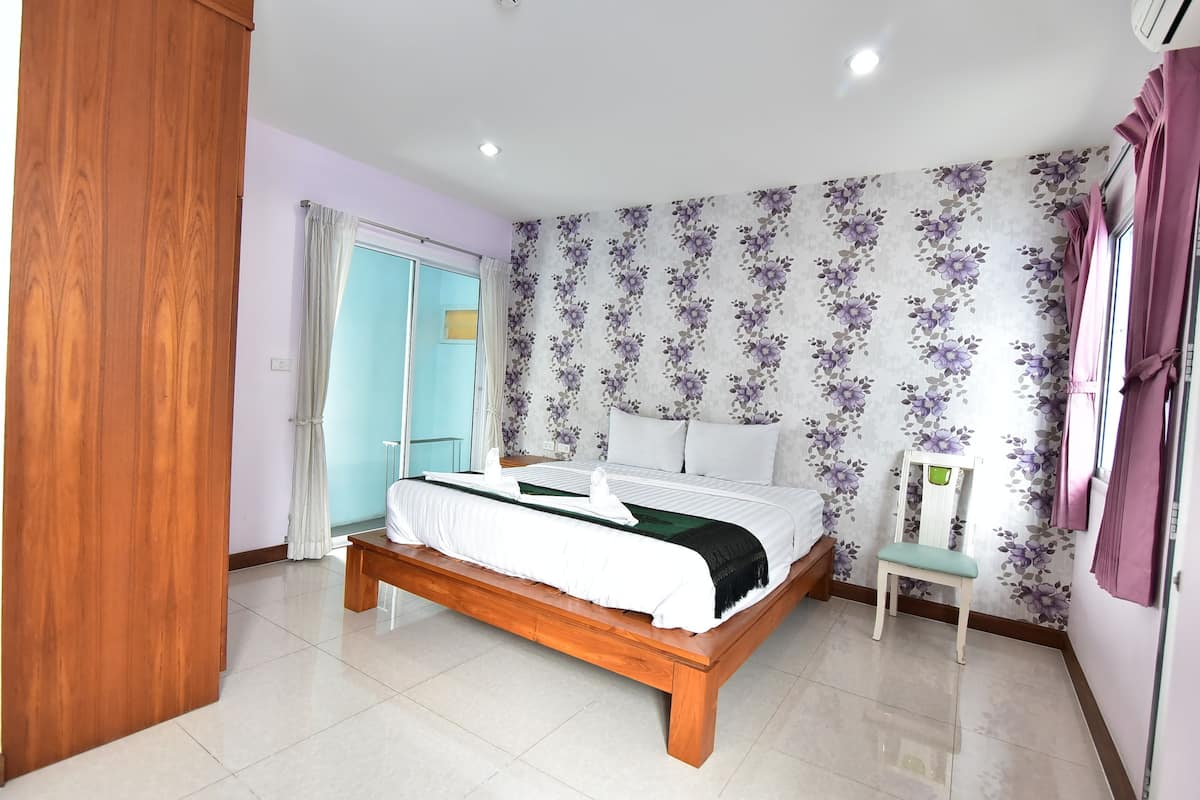 A bedroom with a wooden bed, a bedside table, a chair, a wardrobe, and a window with curtains.