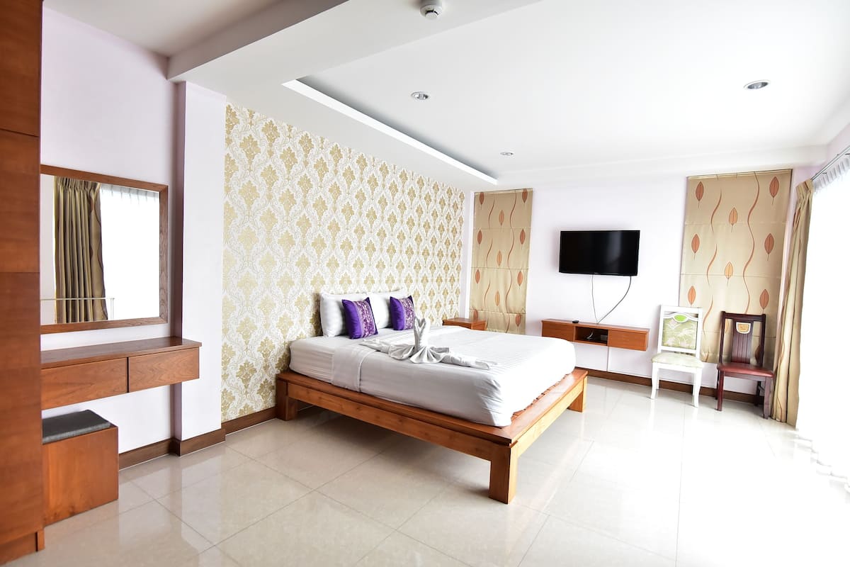 A modern hotel room with a wooden bed, a flat-screen TV, a desk, and a chair.