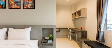 A modern hotel room with a bed, a desk, and a seating area. There are three paintings on the wall.