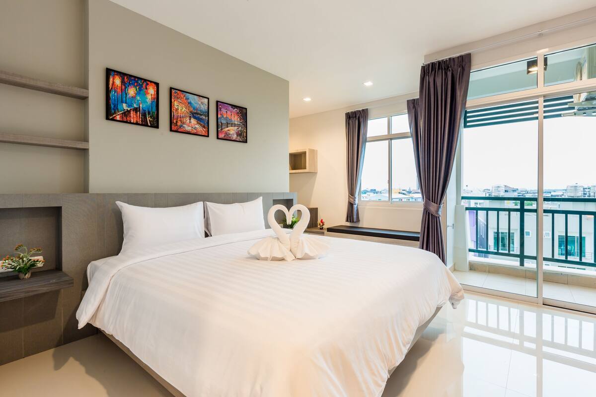 Une chambre d’hôtel moderne avec un grand lit, une vue sur la ville et des œuvres d’art accrochées au mur.
