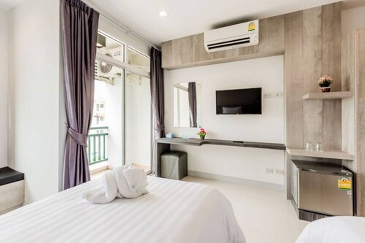 Une chambre d’hôtel équipée d’un lit, d’un téléviseur fixé au mur, d’un petit bureau et d’un appareil de climatisation.
