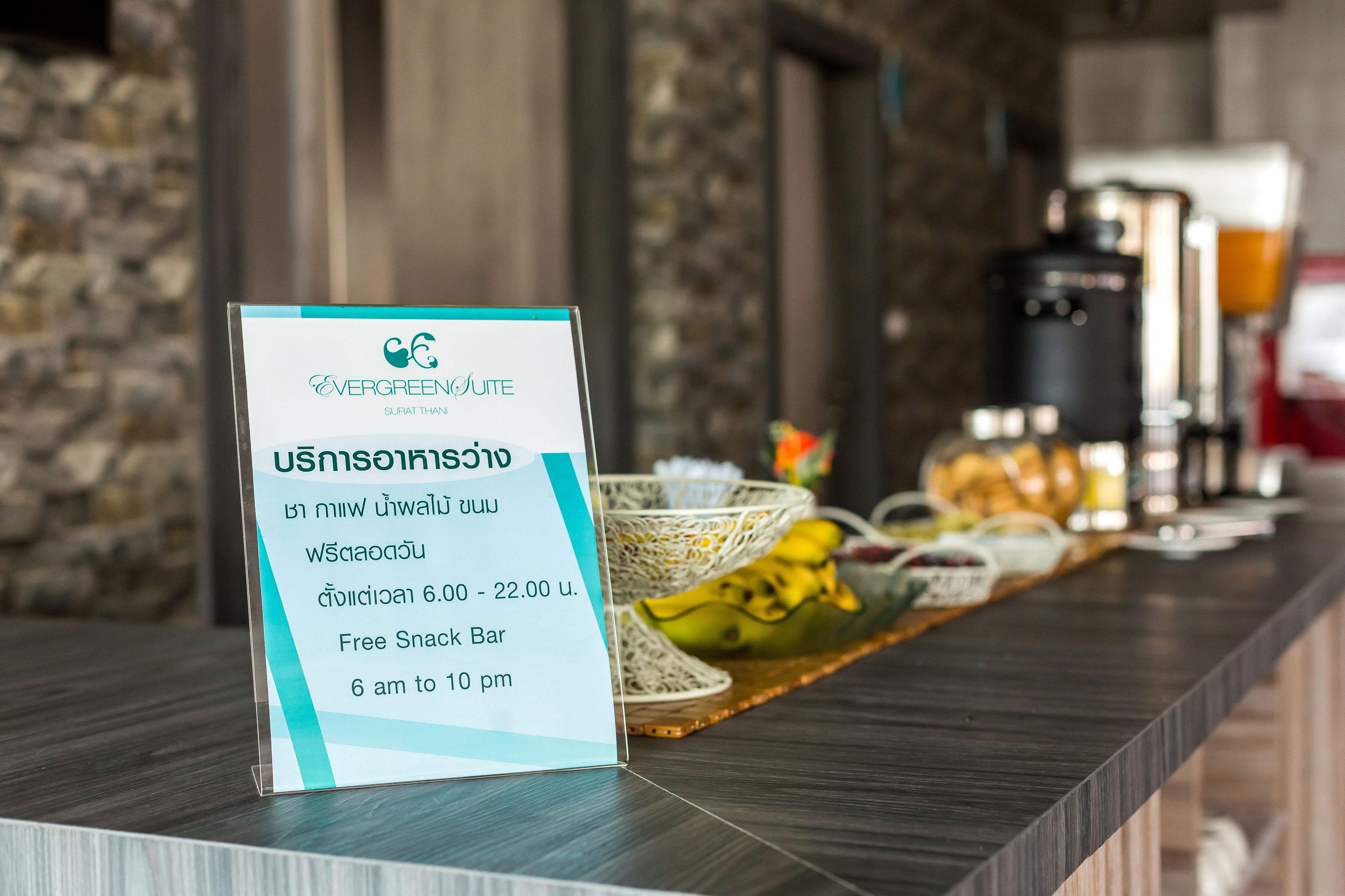 A sign for a free snack bar at a hotel, with a menu board and a counter displaying various snacks and a coffee machine.