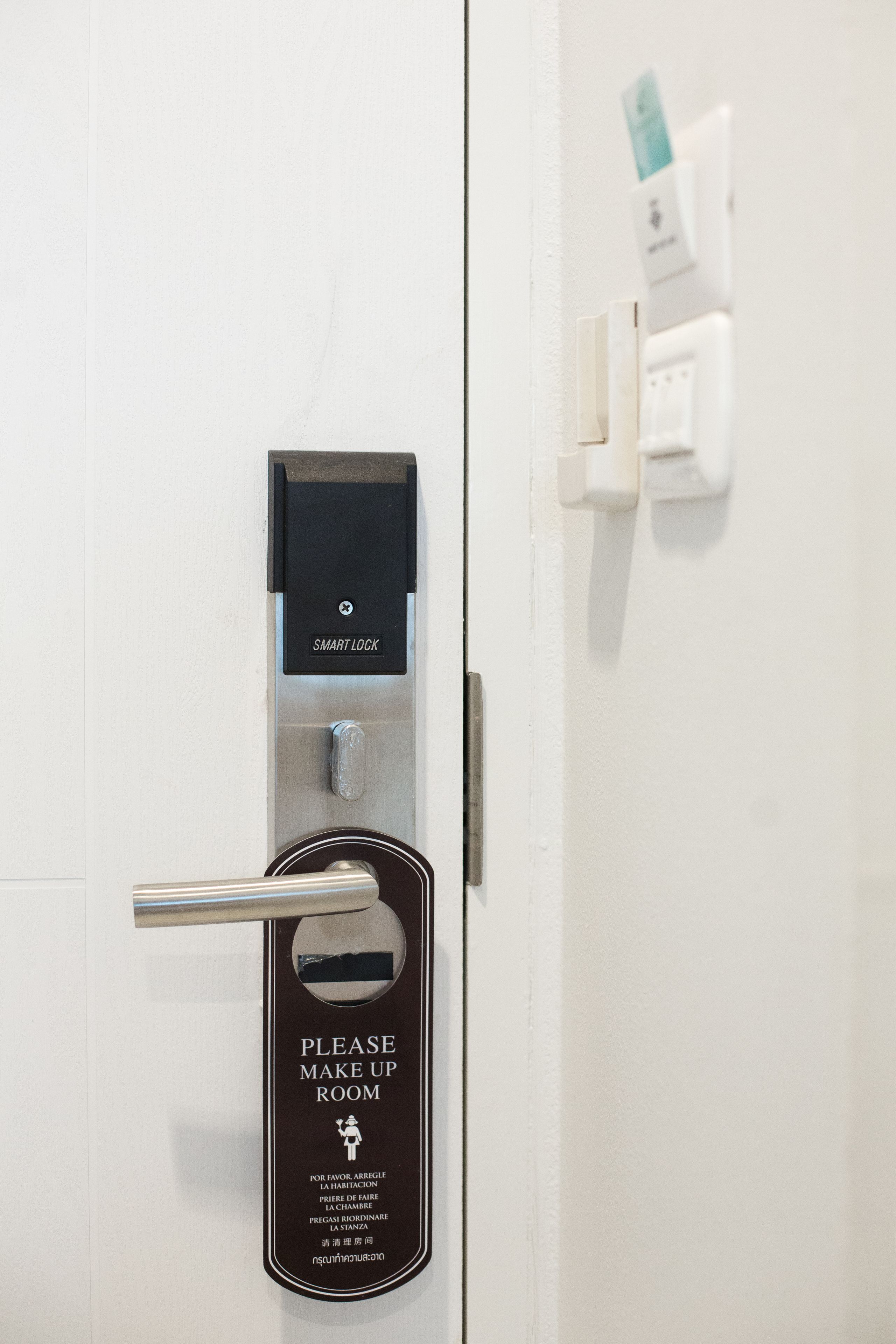 Uma porta com a placa 'Please Make Up Room', uma fechadura inteligente e um leitor de cartão.