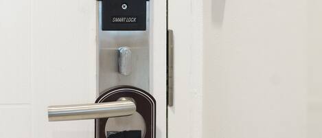 Uma porta com a placa 'Please Make Up Room', uma fechadura inteligente e um leitor de cartão.