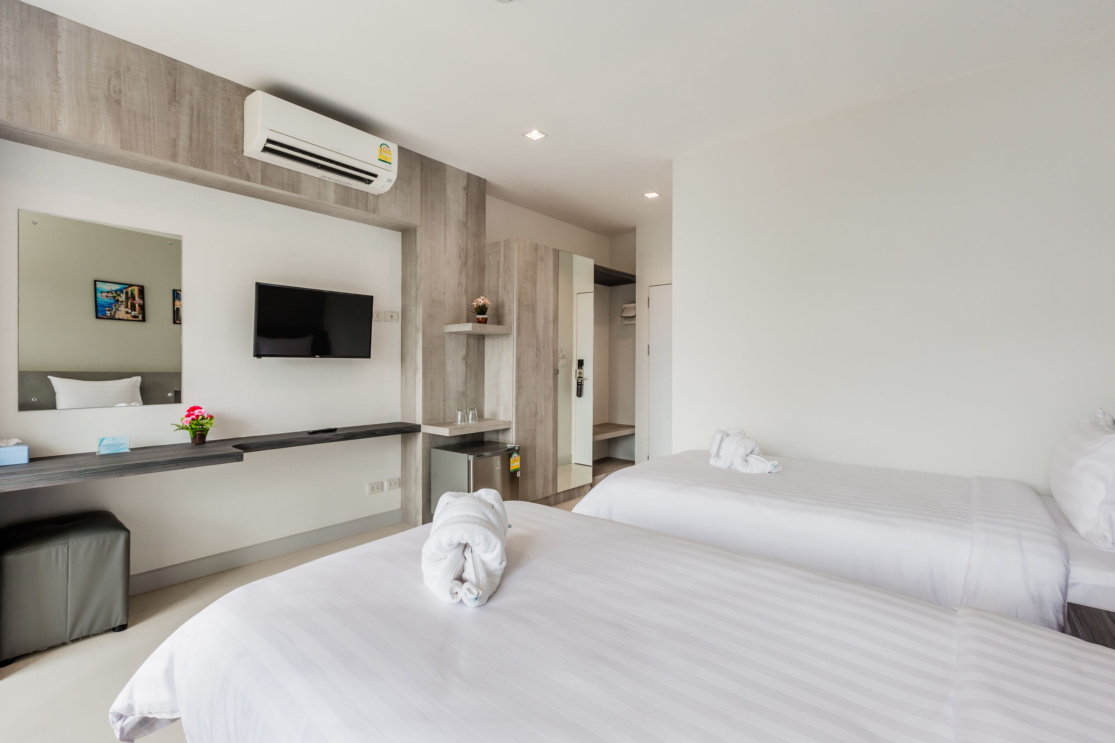 Habitación de hotel con dos camas, televisión, escritorio y baño.